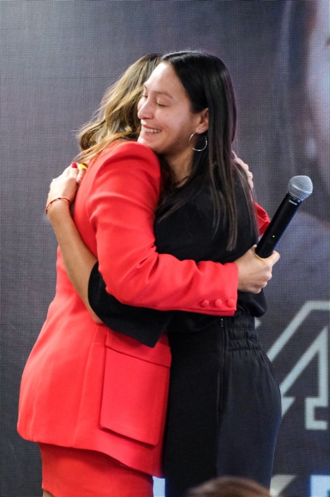 Participante emocionada abraçando Maria Fernanda no palco do CAP Experience